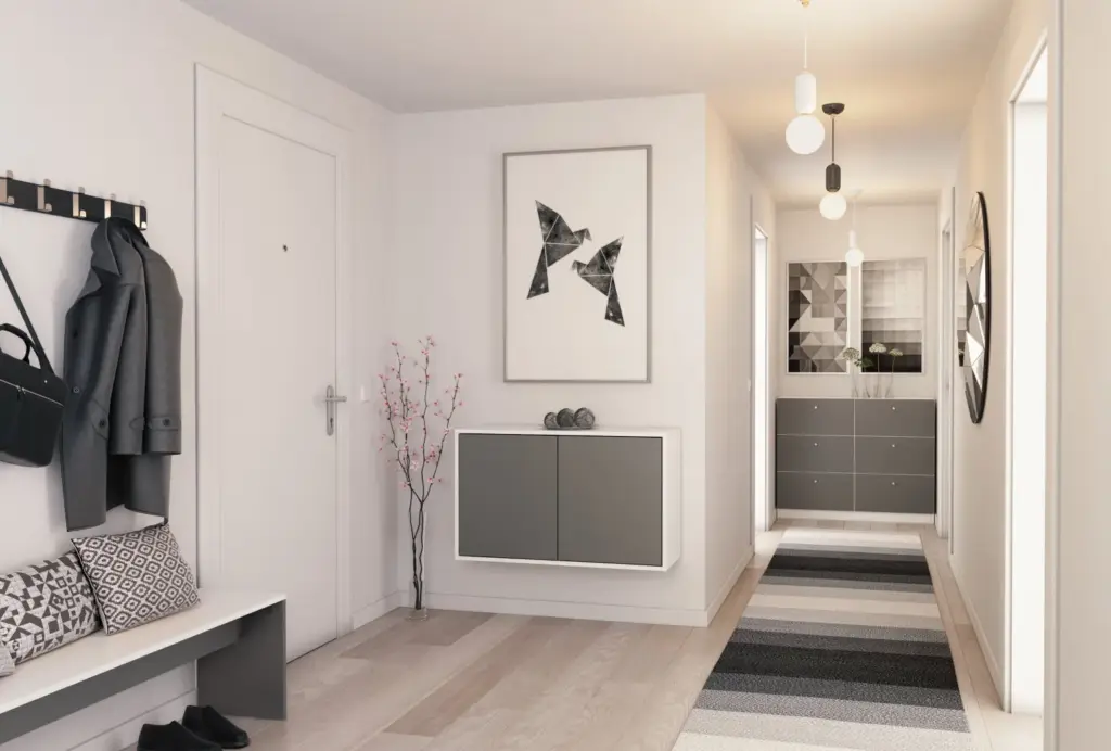 Moderner, hell eingerichteter Flur mit einer grauen Wandkommode und geometrischer Wandkunst darüber. Links befinden sich eine Sitzbank mit gemusterten Kissen und eine Garderobe mit Jacke und Tasche. Auf dem Boden liegt ein gestreifter Teppich in Schwarz-, Grau- und Beigetönen. Der Flur ist mit mehreren Hängelampen beleuchtet, am Ende steht eine weitere graue Kommode mit Dekovase und abstrakten Wandbildern. Ein großer runder Spiegel hängt rechts an der Wand.